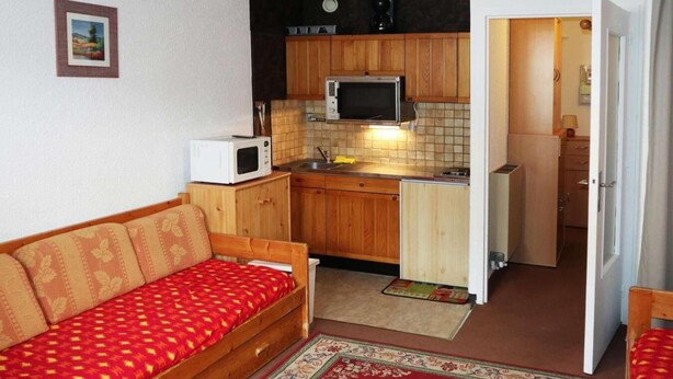 Un espacio habitable compacto con kitchenette, un sofá y un pequeño comedor.