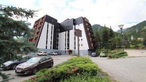 Un edificio moderno con un design angolare unico, caratterizzato da diversi piani e un'area di parcheggio con diverse auto.