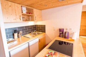 Eine kleine Küche mit Geschirrspüler, Spüle, Kaffeemaschine und Toaster.