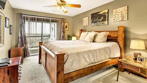 A bedroom with a wooden bed, a ceiling fan, a desk, and a window with curtains.
