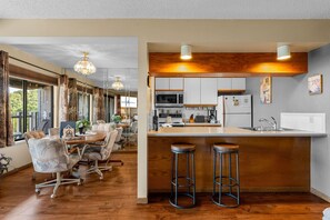A modern kitchen with a bar area, wooden flooring, and large windows. - Lake View Retreat with Boat Slip Included & Free Silver Dollar City Tickets (Branson)