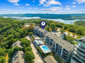 A multi-story hotel with a swimming pool, surrounded by lush greenery and a lake view. - Lake View Retreat with Boat Slip Included & Free Silver Dollar City Tickets (Branson)