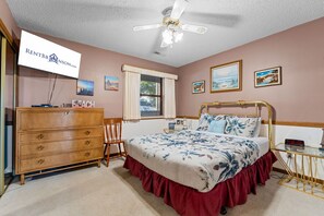Ein Schlafzimmer mit Bett, Schminktisch, Stuhl und Deckenventilator.