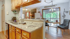 A kitchen with wooden cabinets, a granite countertop, and a dining area with a chair and table. - 1/2 Mi to Marina: Lake Arrowhead Condo! (Waleska)