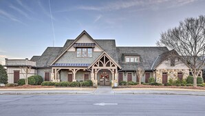 A two-story building with a gabled roof, a central entrance with a decorative archway, and a driveway leading to the entrance. - 1/2 Mi to Marina: Lake Arrowhead Condo! (Waleska)