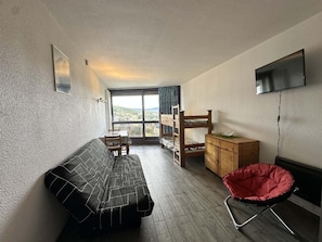 A compact room with a bed, a small table, a chair, a bunk bed, and a red chair. - 7th floor, balcony, parking, tv, 24m², Villard de Lans (Villard-de-Lans)