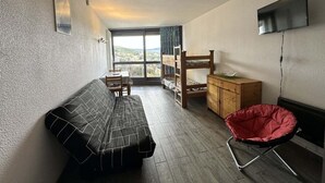 Habitació compacta amb un llit, una taula petita, una cadira, un llit doble i una cadira vermella.