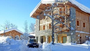 A multi-story building with a stone facade and wooden balconies, surrounded by snow. - Chalet, wifi, sauna, terrace, balcony, fireplace or stove, parking, tv, 250m², Les Arcs (Bourg-Saint-Maurice)