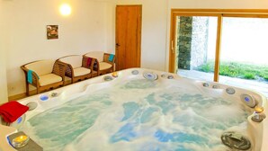 A hot tub with a wooden bench and chairs around it, a wooden door, and a view of greenery through a glass door. - Chalet, wifi, sauna, terrace, balcony, fireplace or stove, parking, tv, 250m², Les Arcs (Bourg-Saint-Maurice)