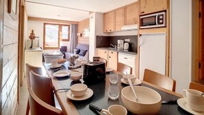 A modern kitchen with wooden cabinets, a microwave, and a dining area with a table set for four.