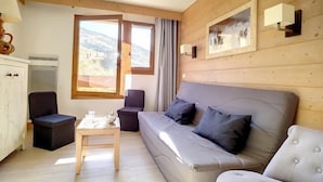 A cozy room with a sofa, two chairs, a small table, and a window with a view of the mountains.