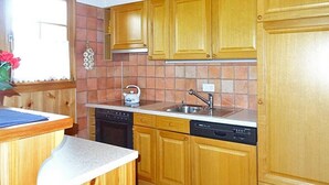 Una cocina con armarios de madera, lavavajillas, pileta y tetera.