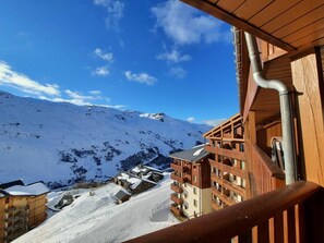 Un bâtiment en bois doté de balcons qui offrent une vue sur un paysage montagneux enneigé.