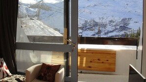 A room with a large window offering a view of a ski lift and snowy mountains. - Ski-in/ski-out & foot of the slopes, 2nd floor, balcony, tv, 19m², Les Menuires (Les Menuires)