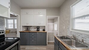 Een moderne keuken met grijze kastjes, een zwarte kookplaat en een houten aanrecht.