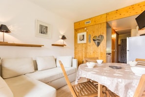 A cozy room with a sofa, a dining table with chairs, and a kitchen area visible through an open door. - 50m from resort center, 8th floor, view valley, balcony, tv, 24m², Les Arcs (Les Arcs)