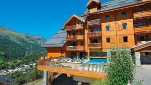 A multi-story wooden building with balconies and a pool area.