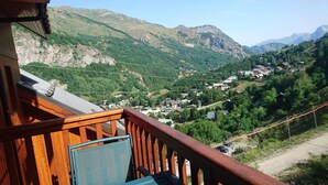 A wooden balcony with a view of a valley and mountains.