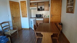A dining area with a wooden table and chairs, a microwave, and a refrigerator.