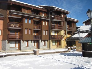 Ein mehrstöckiges Holzgebäude mit Balkonen, einem Steinsockel und verschneitem Grund.