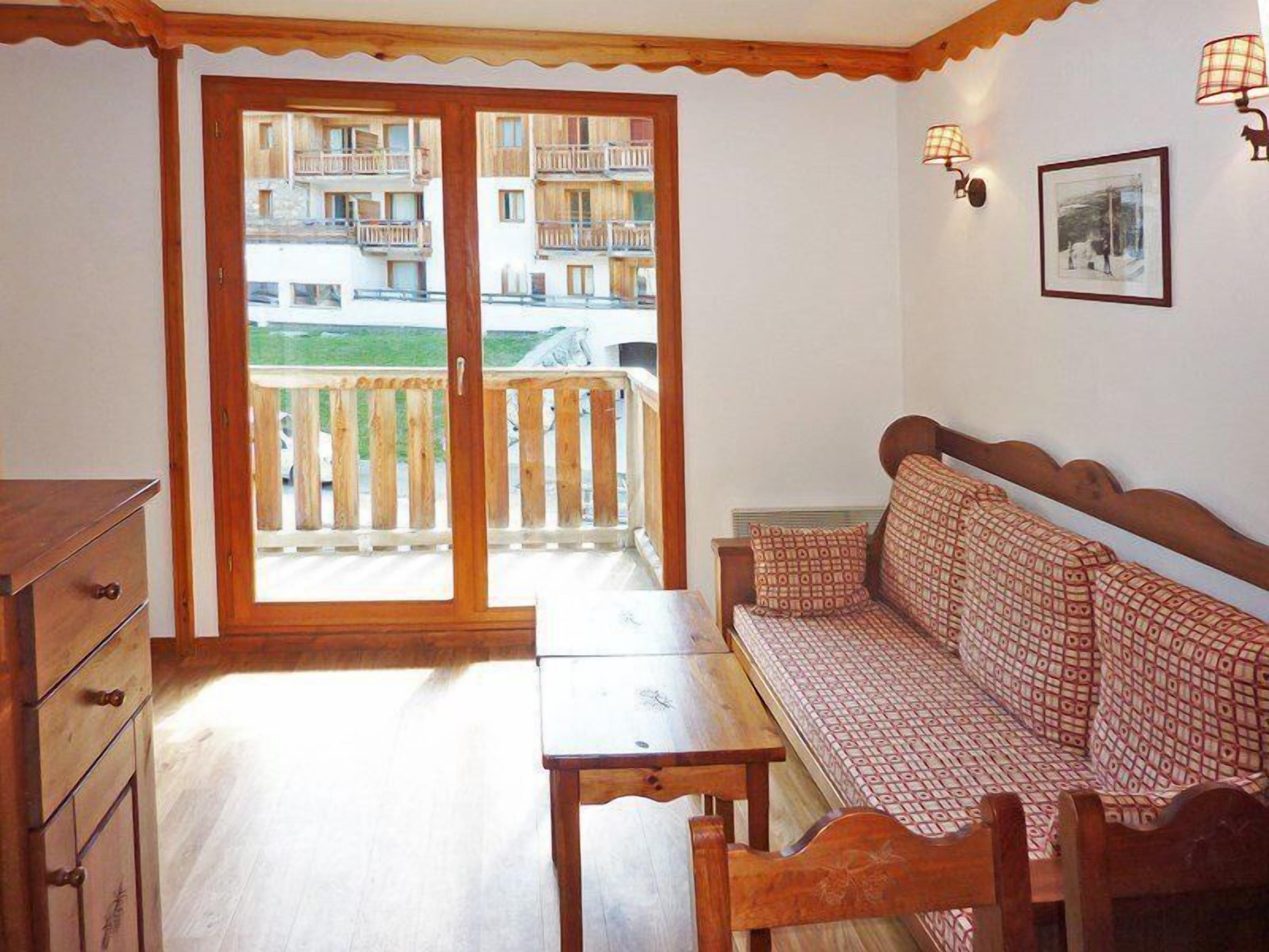 Ein Zimmer mit einer hölzernen Bank, einem kleinen Tisch und einer Schiebetür zum Balkon.