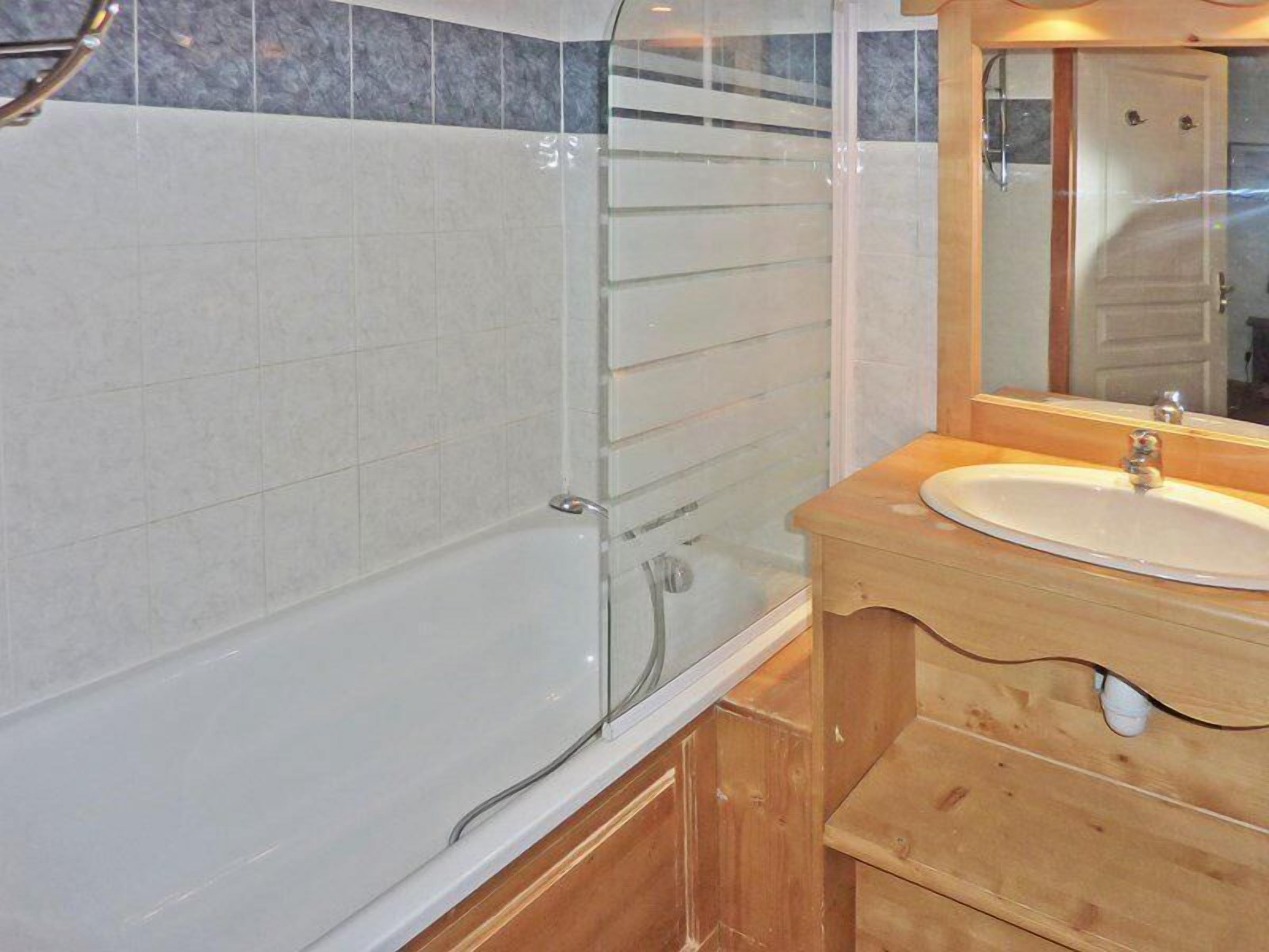 Une salle de bain avec une douche à parois de verre, un meuble-lavabo en bois et un miroir au-dessus du meuble-lavabo.