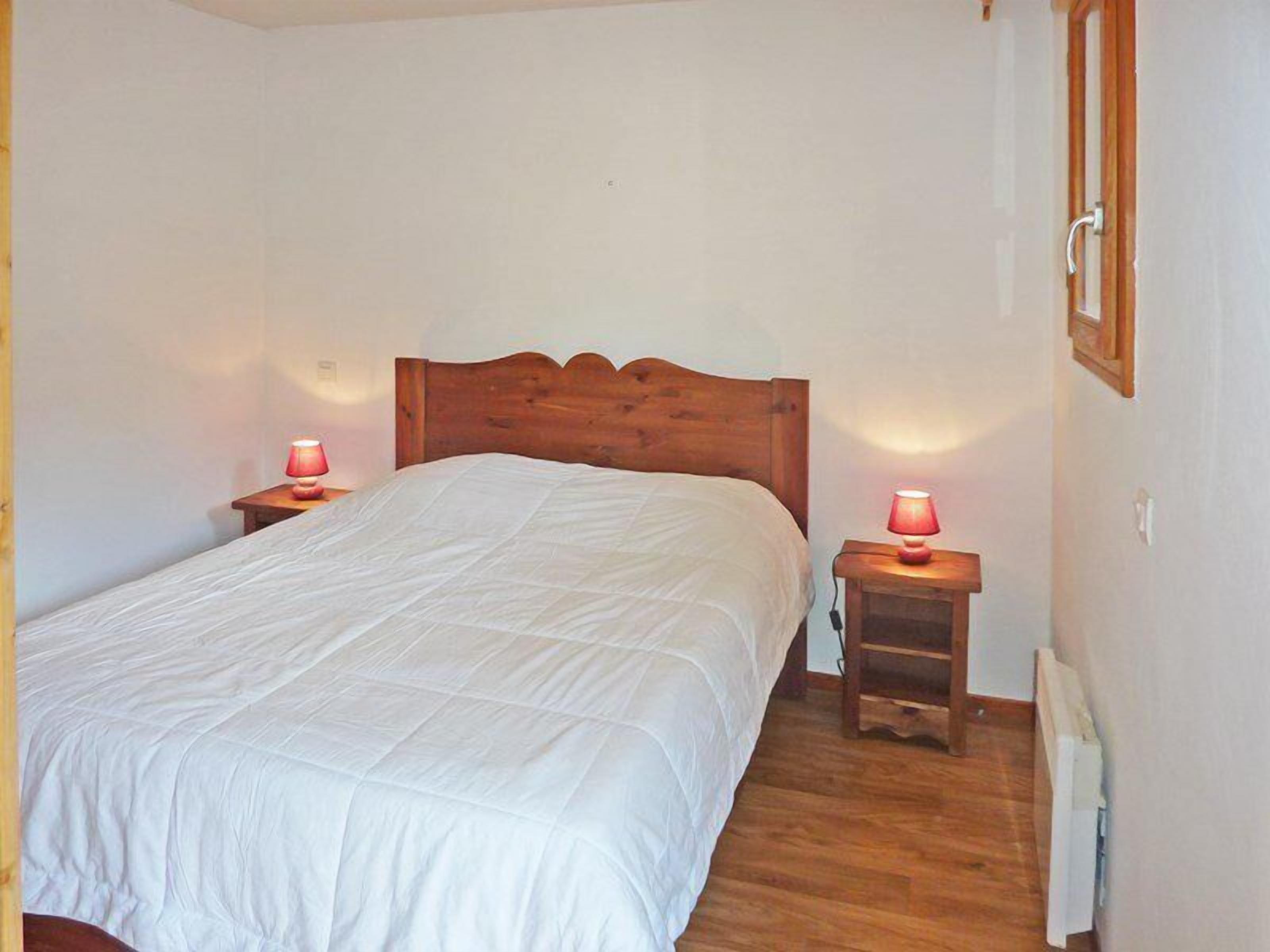 A bedroom with a wooden bed, two bedside tables with lamps, and a radiator on the wall.