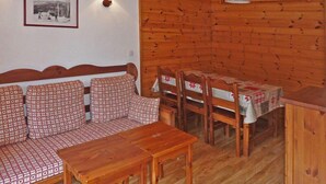 Ein Holzinnenraum mit einer Couch, Sesseln, einem Tisch und einer Lampe.