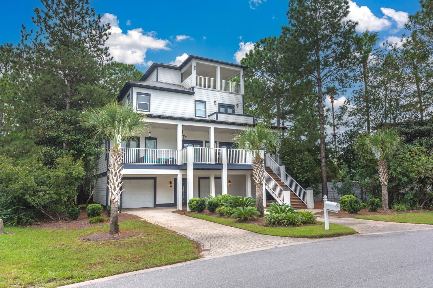 A two-story building with a balcony on the upper floor, surrounded by trees and a well-maintained lawn.