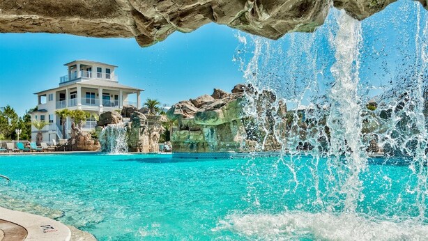 A pool with clear turquoise water, a waterfall feature, and a building in the background. - 2 min to the beach with 30A's largest pool, plus stunning decks, and 4 bikes (Santa Rosa Beach)