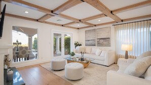 Un salon moderne avec un canapé blanc, des poufs, une table basse en verre et une cheminée.