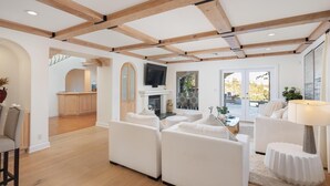 Un salon spacieux avec une cheminée, des canapés blancs et un téléviseur.