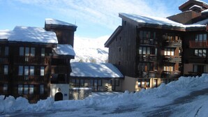 Un bâtiment enneigé, doté de nombreux balcons et d’une structure en pierre à l’avant.