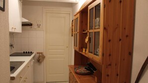 A compact kitchen with white cabinets, a stove, and a wooden cabinet with glass doors. - 250m from ski slopes, 6th floor, parking, tv, ski locker, 50m², Vars (Vars)