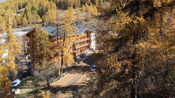 A multi-story building with a ski lift in the background, surrounded by autumn-colored trees. - 250m from ski slopes, 6th floor, parking, tv, ski locker, 50m², Vars (Vars)