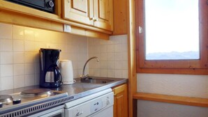 A compact kitchen with wooden cabinets, a coffee maker, a kettle, and a dishwasher. - 10m from ski slopes, 3rd floor, balcony, ski locker, 41m², Méribel-Mottaret (Méribel - Les Allues)