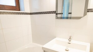 A bathroom with a white bathtub, a white sink, and a mirror above the sink. - 130m from ski slopes, 1st floor, balcony, parking, tv, ski locker, 27m², La Norma (La Norma)