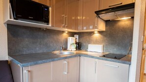 A compact kitchen with a microwave, sink, and countertop appliances.