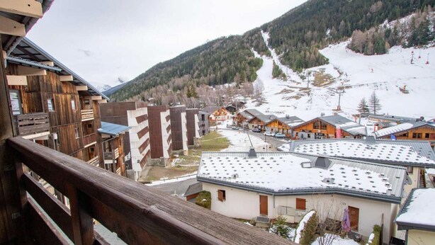 A mountain town with wooden buildings, a ski slope, and a view of the surrounding mountains. - 130m from ski slopes, 4th floor, balcony, parking, tv, ski locker, 35m², La Norma (La Norma)