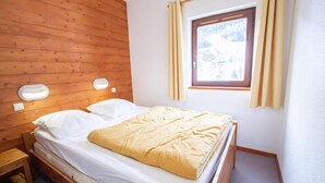 A single bed with a wooden headboard, a window with curtains, and a bedside table. - 130m from ski slopes, 4th floor, balcony, parking, tv, ski locker, 35m², La Norma (La Norma)