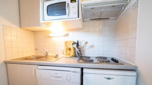 Une petite cuisine équipée d’un four à micro-ondes, d’une machine à café, d’une cuisinière et d’un lave-vaisselle.