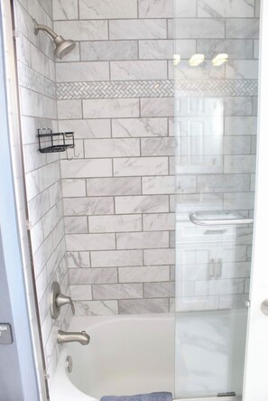 Een bad/douchecombinatie, een bubbelbad, een haardroger, handdoeken