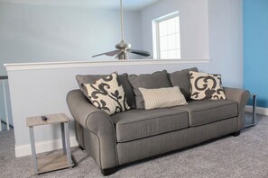 Relax in this inviting living room with a sofa, side table, and ceiling fan.