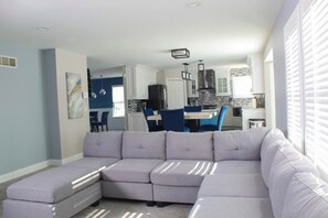 Relax in this stylish living room with a comfortable sofa, dining area, and modern kitchen.