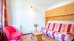 Una sala de estar acogedora con un sillón rojo, una mesa de centro de madera y un sofá a rayas.