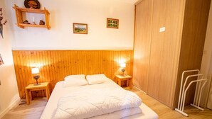 Une chambre à coucher avec une tête de lit en bois, deux tables de chevet avec des lampes, un lit avec une literie blanche et une armoire en bois.