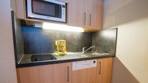 A compact kitchenette with a microwave, coffee maker, sink, and dishwasher.