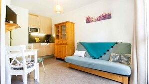 A compact living space with a kitchenette, a sofa, and a dining area.