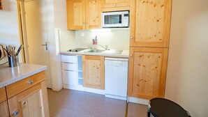 A compact kitchen with wooden cabinets, a microwave, a dishwasher, and a sink. - 100m from ski slopes, 2nd floor, balcony, parking, tv, 47m², La Norma (La Norma)