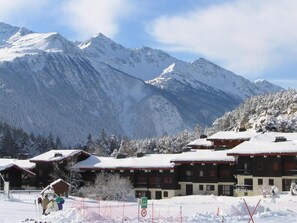 Een bergresort bedekt met sneeuw, met chalets, skipistes en een helder uitzicht op de omliggende bergen.